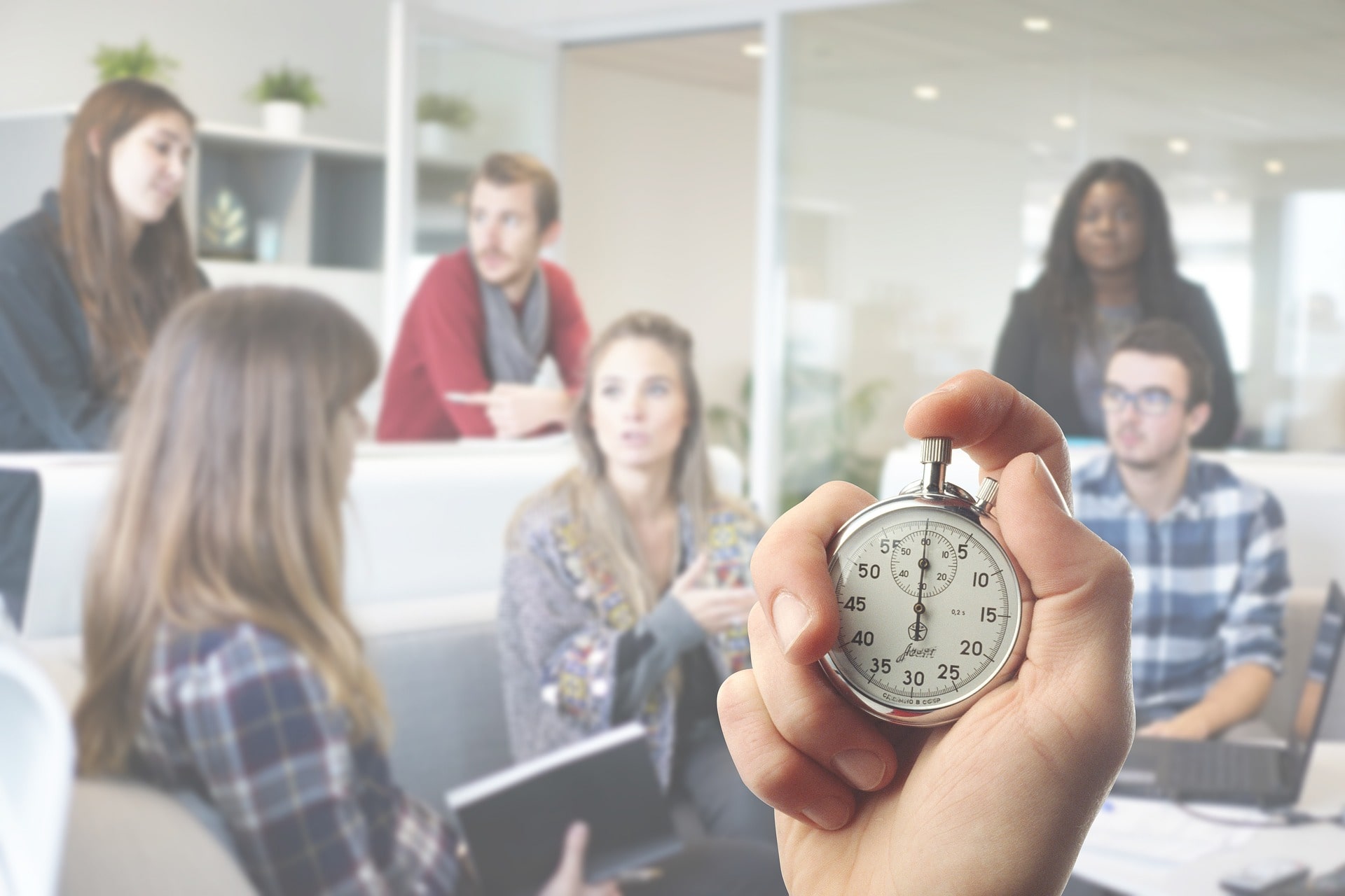 Eine Stoppuhr im Vordergrund und Personen im Hintergrund.