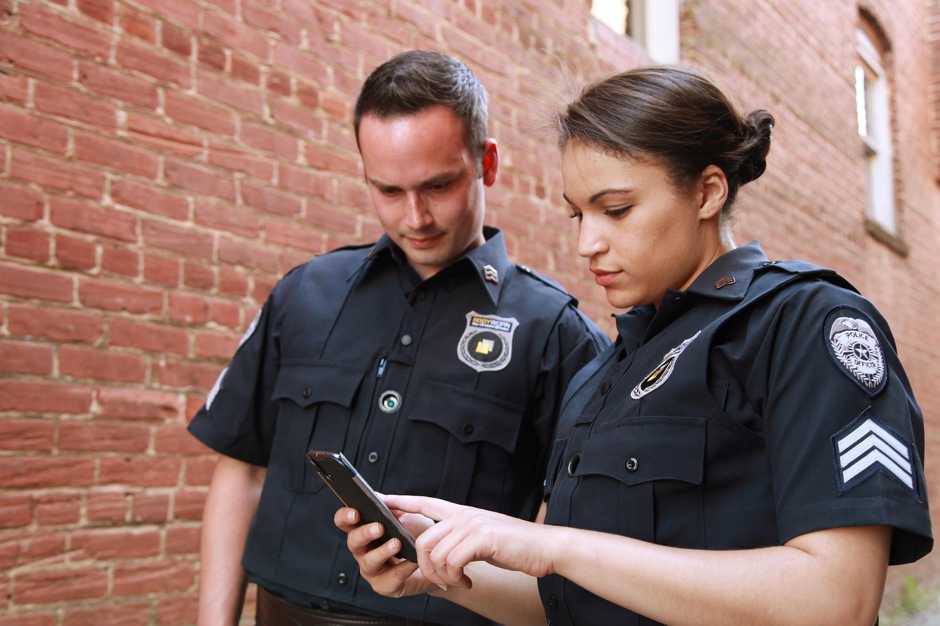 2 Polizisten schauen gemeinsam auf ein Mobiltelefon