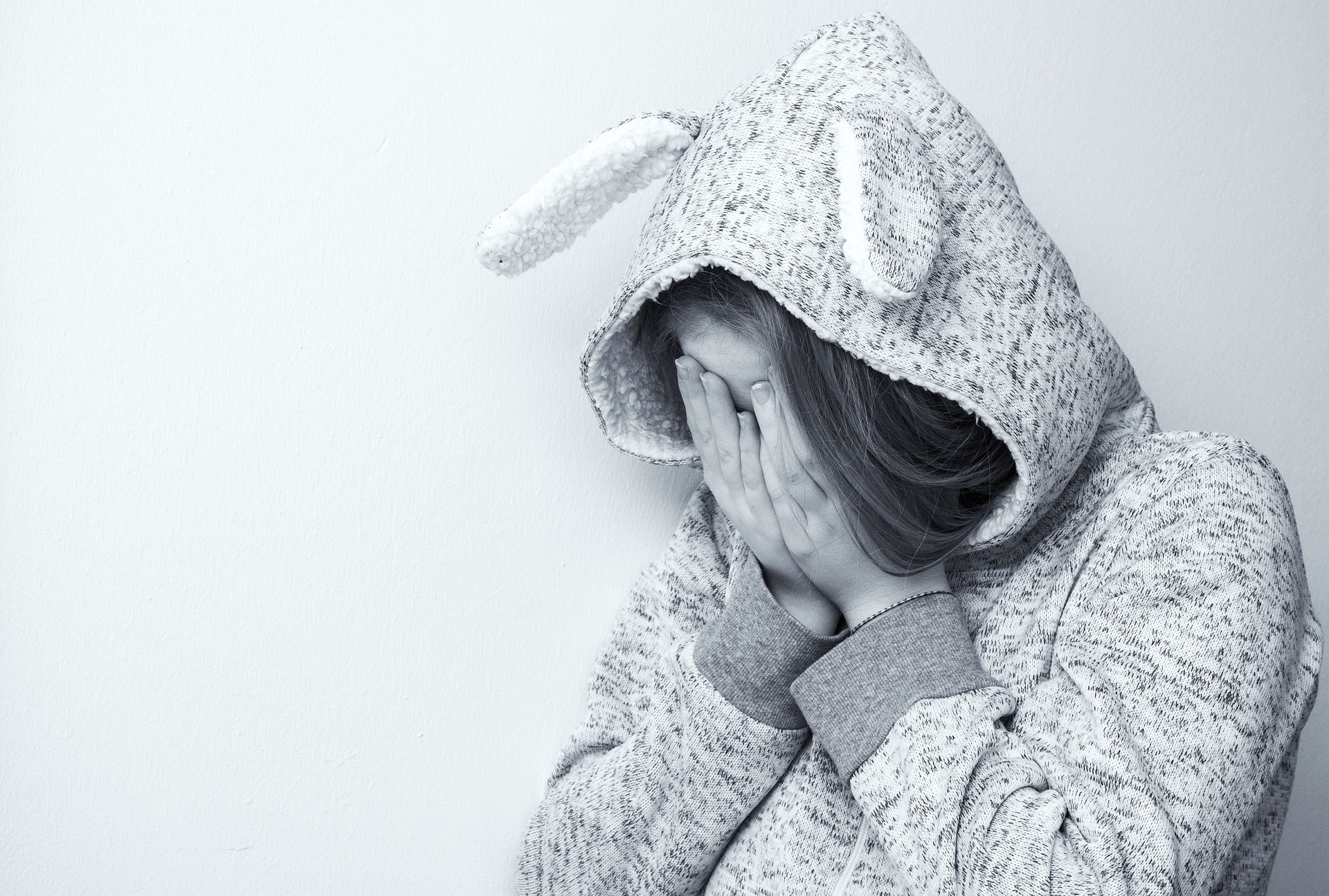 Verzweifelte Frau, welche die Hände vor das Gesicht hält