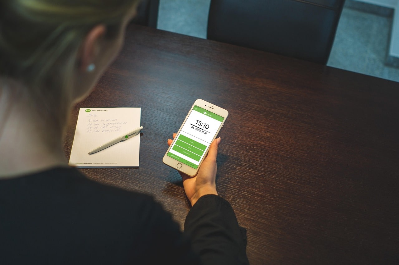 Mitarbeiterin im Homeoffice erfasst Arbeitszeit auf dem Smartphone